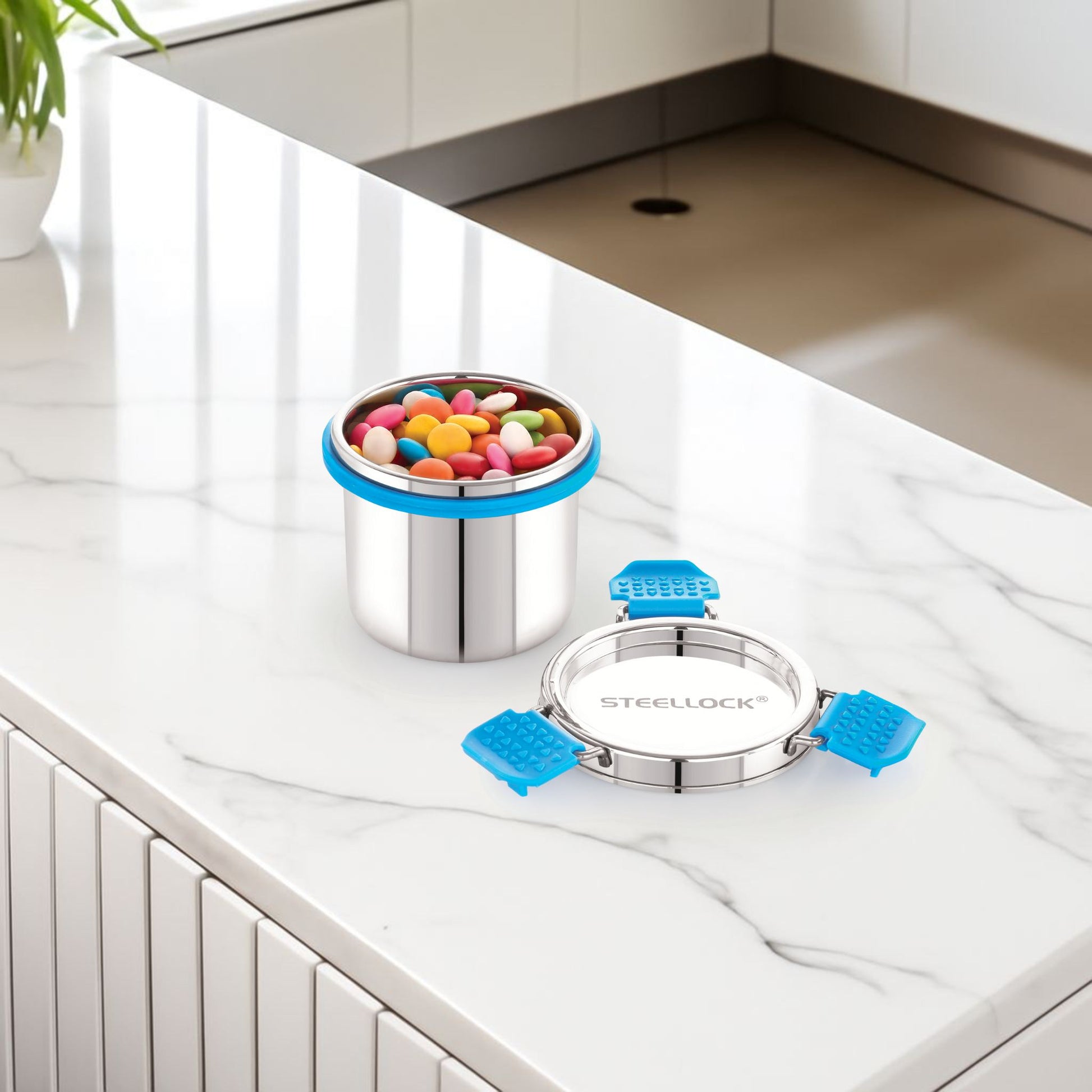 Stainless steel container with blue lids on a kitchen counter, filled with colorful candies.