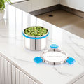 Stainless steel container with green food on a kitchen counter, featuring the brand 'Steelock'.