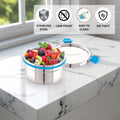 Stainless steel container with fruits on a marble surface, featuring lockable lid.