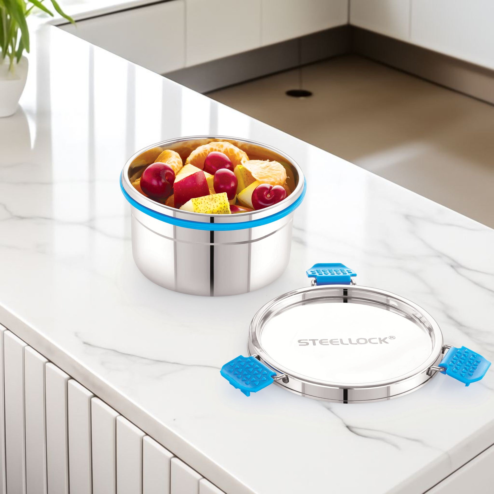 Stainless steel lunch box with fruit inside on a kitchen counter, featuring the brand 'Stellock'.