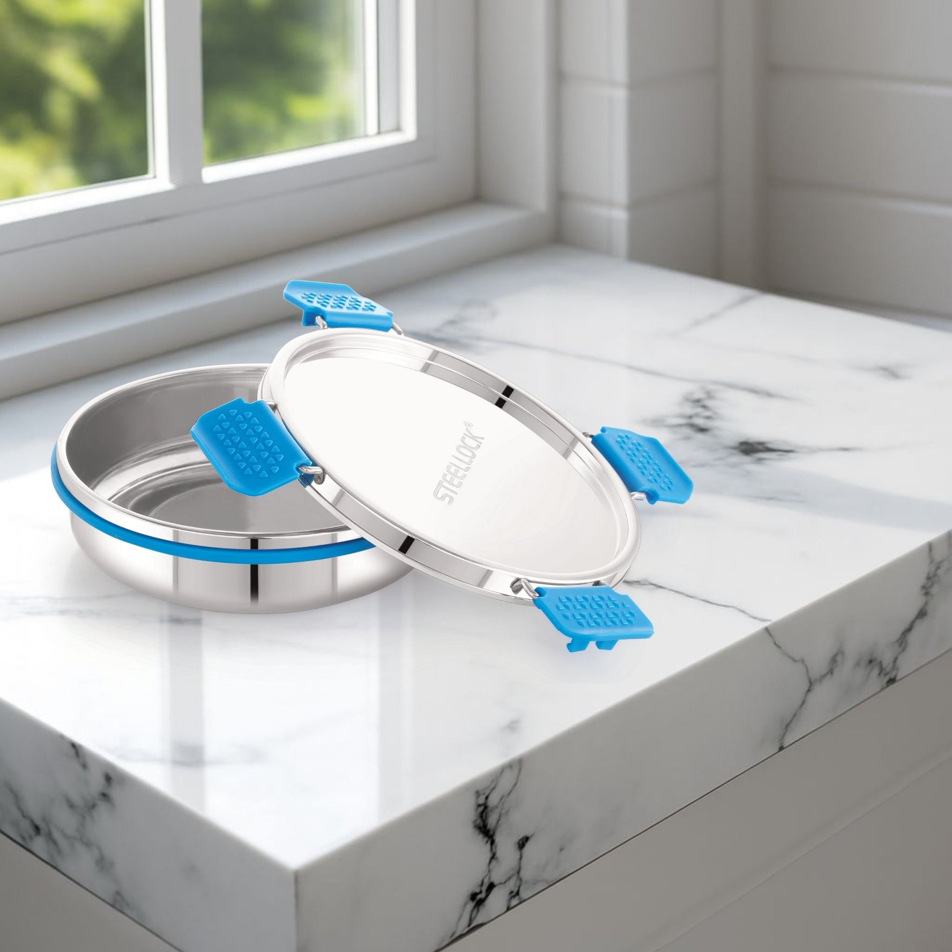 Stainless steel container with blue lids on a marble surface near a window